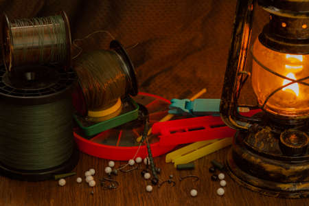 fishing line, hooks, sinkers, tools illuminated by an antique kerosene lampの写真素材