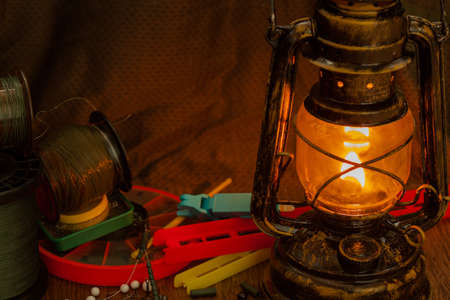 fishing line, hooks, sinkers, tools illuminated by an antique kerosene lampの写真素材