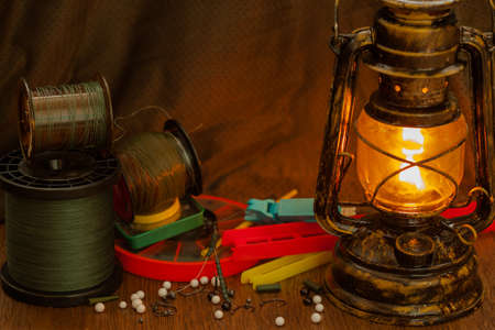 fishing line, hooks, sinkers, tools illuminated by an antique kerosene lampの写真素材