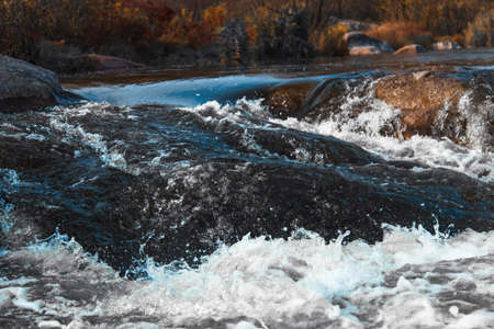 Stormy river rolls over stonesの写真素材