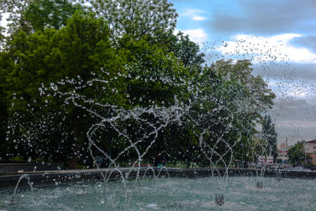 splashes of water close-up from the fountain against the background of the city parkの写真素材