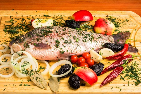 Fresh raw carp with vegetables, fruits and spices on wooden board.の写真素材