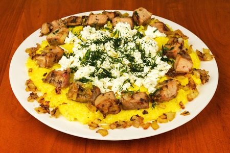 Kulesha, mamalyga, polenta with meat and homemade cheese on the plate, traditional Urkainian and Hutsul meal