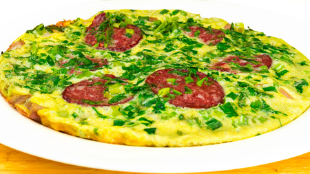 Omelette with sausage and herbs in white plate on wooden table, selective focus, close-up.の写真素材