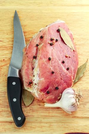 Raw meat before cooking with spices, garlic and knife on wood cutting board.の写真素材