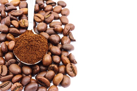 Ground coffee spoon on coffee beans, isolated on white background, with space for textの写真素材
