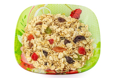 Cereal muesli or oat flakes with dried fruit on plate, isolated on white background, top viewの写真素材