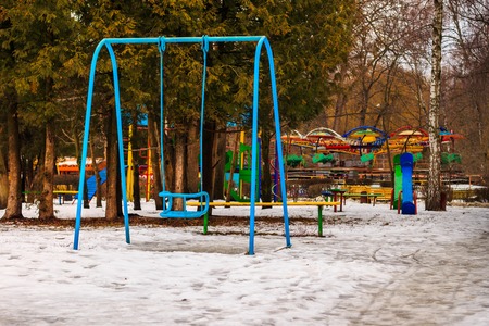 Empty blue swing and children playground in winter park, outdoors.の写真素材