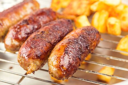Burned, grilled meat sausages with fried potatoes, selective focusの写真素材