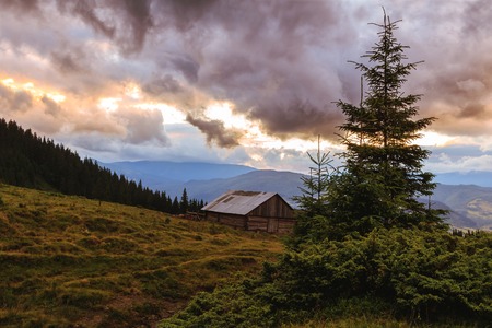 Picturesque Carpathian mountains landscape. House under hill, scenery of sunsetの写真素材