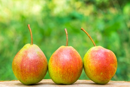 Three ripe organic pears on wooden board, blurred background, selective focusの写真素材