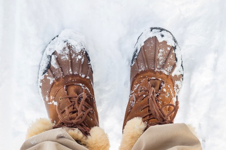 Top view in warm man brown boots with fur on white snowの写真素材