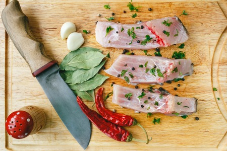 Fresh uncooked three pieces of silver carp fish with red chile pepper, bay leaf, garlic, spices and...