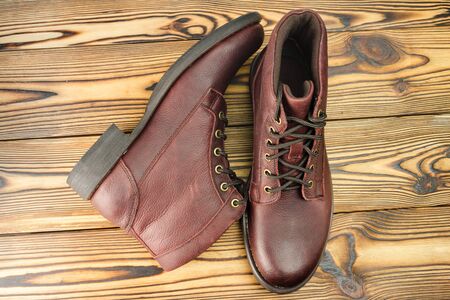Stylish brown leather boots for men on wooden background, top view