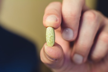 Male hand holding and show of vitamin or medical pill, close-upの写真素材