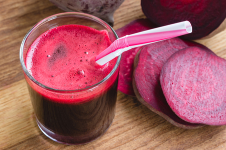 Fresh beet juice in glass and sliced beetroot on wooden tableの写真素材