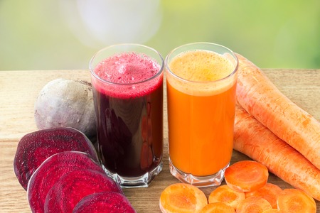 Two glass of fresh beet and carrot juice, beetroot and carrots vegetable on wooden table, defocused, nature backgroundの写真素材