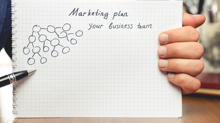 Man shows presentation of business concepts network marketing and business structures diagram in notepad at the tableの写真素材