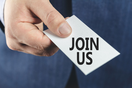 Business man in blue suit, close-up of hand showing card with text join us