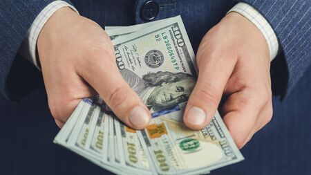 Close-up of male hands hold hundred dollars banknotes, business and finance concept