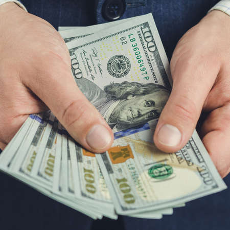 Close-up of male hands hold hundred dollars banknotes, business and finance conceptの写真素材