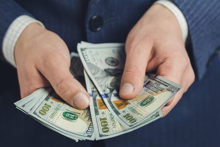 Close-up of male hands hold hundred dollars banknotes, business and finance conceptの写真素材