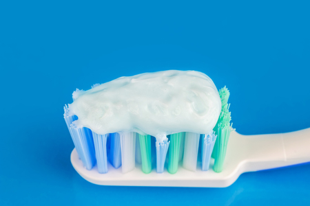 Toothpaste on the toothbrush at blue background, macro imageの写真素材