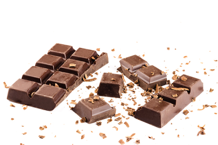 Pieces of dark chocolate bar, cubes, sprinkled with grated chocolate, isolated on white background.の写真素材