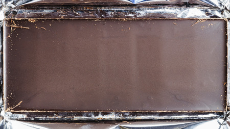 Bitter, dark chocolate bar in foil, top view, space for your text.の写真素材