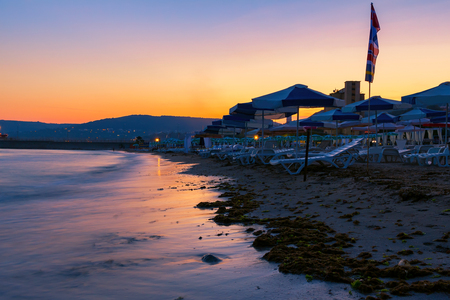 Beach with umbrellas on black sea coast at dusk after sunset in Balchik city.の写真素材
