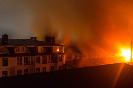 Building in fire at the night , burning fire flame with smoke on the apartment house roof.の写真素材