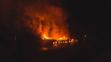 Building in fire at the night , burning fire flame with smoke on the apartment house roof.の写真素材