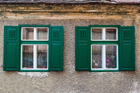 Detail of facade with two old windows in rustic ancient house in Sibiu city, Romania.