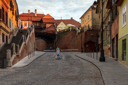 SIBIU, ROMANIA - JUNE 19, 2017: View on the medieval street with people, bridge of Lies and ancient houses at the sunset time.のeditorial素材
