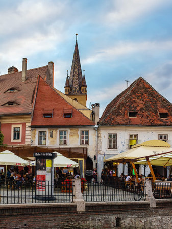 SIBIU, ROMANIA - JUNE 19, 2017: View on the Lutheran Cathedral tower in the street with medieval...