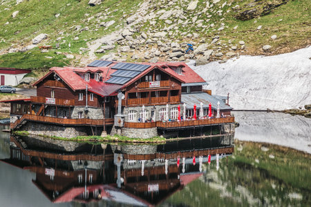 BALEA LAKE, ROMANIA - JUNE 20, 2017: House reflected in water of glacier lake Balea in Carpathian mountains.のeditorial素材