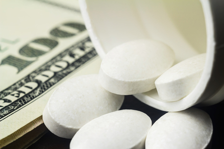 White pills of calcium, vitamin supplement, medical tablets in bottle on dollar banknote, macro image.の写真素材