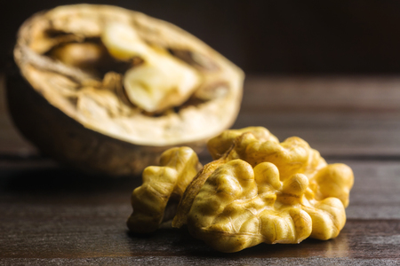 Half of walnut kernel and half walnut in shell on dark wooden background.の写真素材