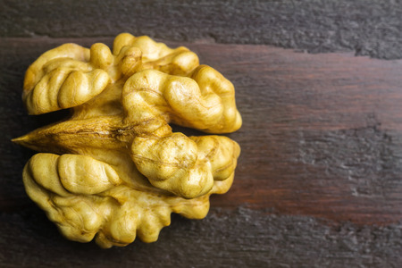 Half of walnut kernel on dark wooden background, top view.の写真素材