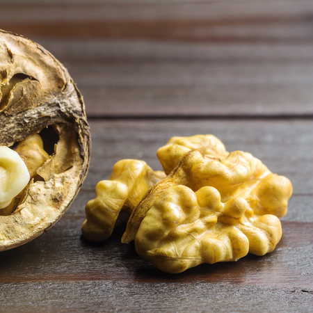 Half of walnut kernel and half walnut in shell on dark wooden background.の写真素材
