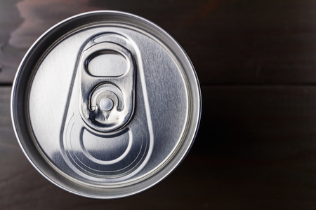 Aluminum beverage can of soda or beer on wooden table, top view.
