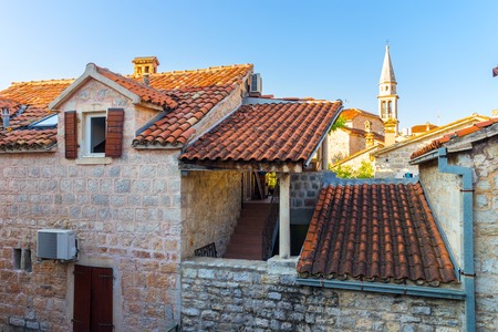 Facade of old historical buildings and high church tower in central district at ancient city Budva, Montenegro.の写真素材
