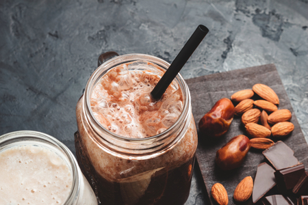 Chocolate smoothie in a jar, protein milkshake, nuts, chocolate cubes, dates, cinnamon sticks, healthy eating on a dark background.の写真素材