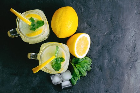 Refreshing lemonade drink with lemon slice and mint in the jar on dark background, top view.の写真素材