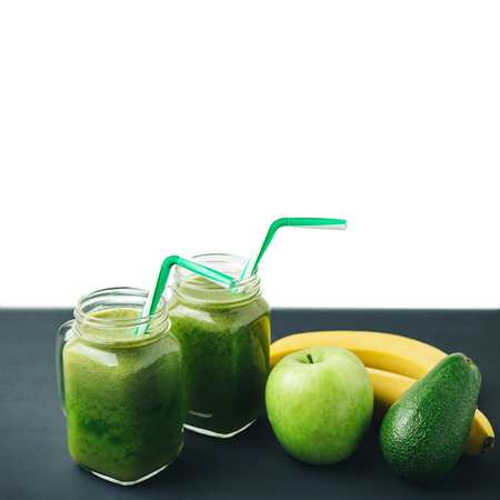 Green, healthy, detox smoothie from avocado, banana, apple in mason jar on dark table, isolated on white background.の写真素材