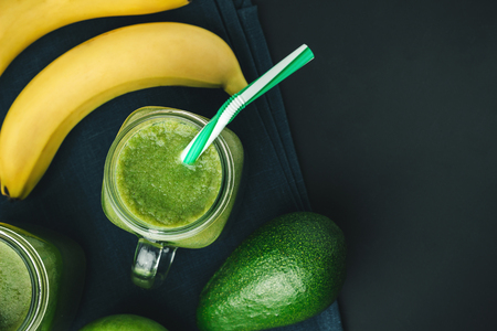 Green, healthy, detox smoothie from avocado, banana, apple in mason jar on dark background, vegetarian food, top view.の写真素材