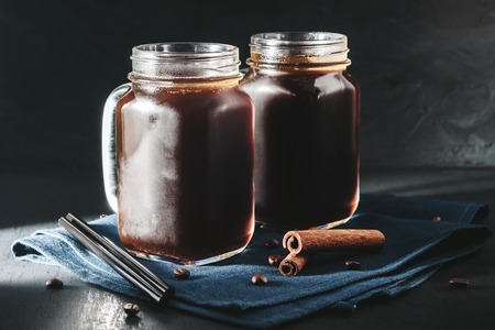 Coffee with ice in a glass mason jars on the napkin at dark background.の写真素材