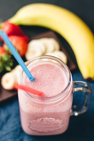Smoothie with strawberry and banana in the jar at dark background.の写真素材