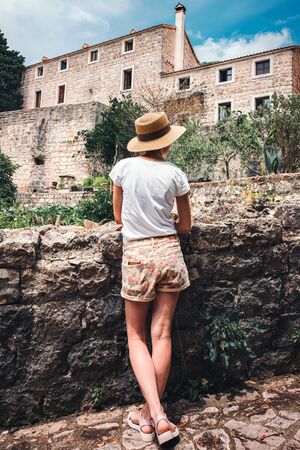 Rear view of young woman who looking to the ancient stone building in Budva city, Montenegro.の写真素材