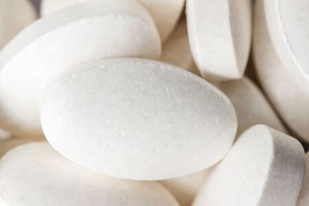 Group of white medical supplement pills, macro image.